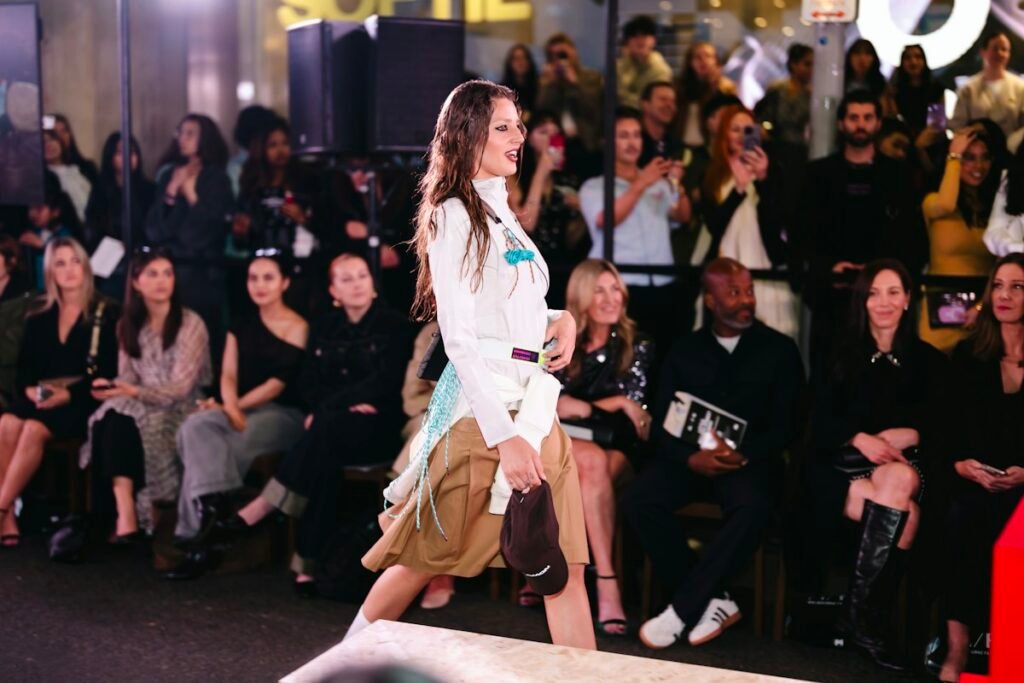 Modelo profesional en una pasarela con asistentes al desfile.